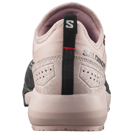 A close-up rear view of a Salomon shoe in light beige and pinkish-beige, featuring a black heel pull tab with the Salomon 'S' logo and 'SALOMON' branding.