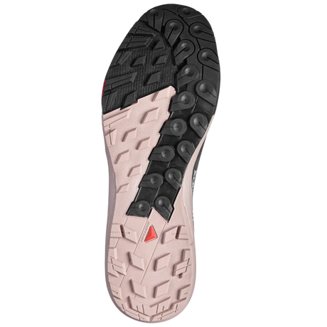The outsole of a trail running shoe, showing a black treaded section on the heel and a light pinkish-beige section on the forefoot with a small red triangular logo.