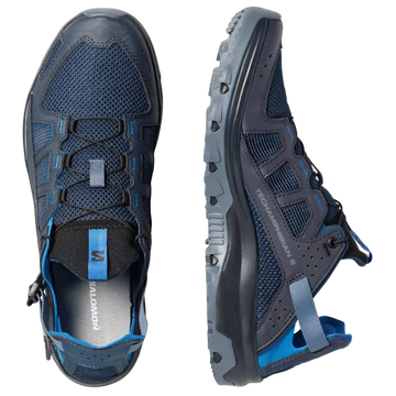 A pair of Salomon hiking shoes shown from two angles: a top-down view and a side profile view. The shoes are dark navy blue with black overlays, blue mesh details, and bright blue accents on the laces and heel pull tabs, set against a solid light gray background.