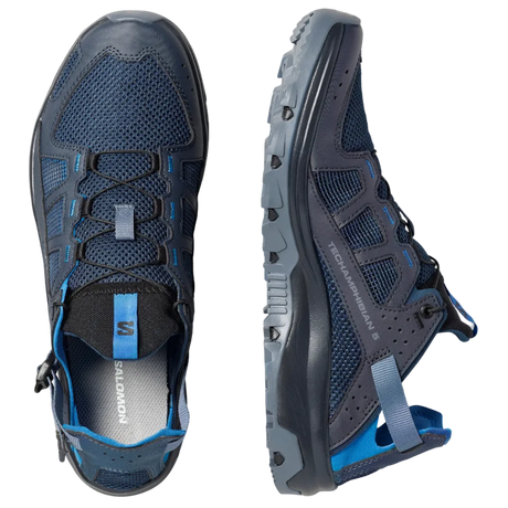 A pair of Salomon hiking shoes shown from two angles: a top-down view and a side profile view. The shoes are dark navy blue with black overlays, blue mesh details, and bright blue accents on the laces and heel pull tabs, set against a solid light gray background.