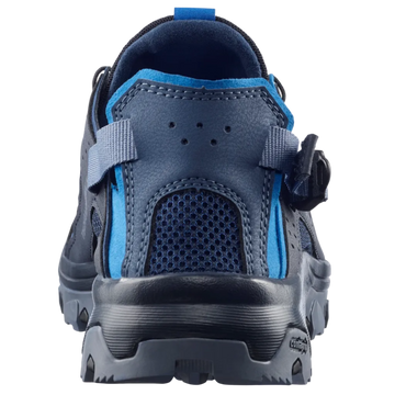 A close-up rear view of a dark blue and bright blue athletic shoe with a hook-and-loop strap closure, set against a light gray background.