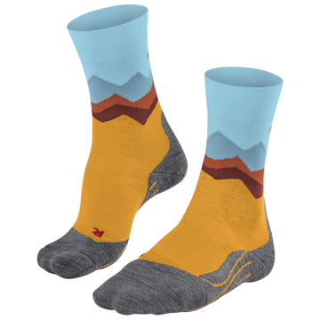 A pair of crew socks with a mountain landscape pattern, featuring a mustard yellow body, gray toe and heel areas, and light blue and brown mountain peaks on the cuff.