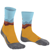 A pair of crew socks with a stylized mountain landscape print. The design features a light blue cuff, layered brown and gray mountains, a mustard yellow midsection, and a heather gray toe and heel.