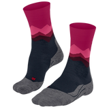 A pair of crew socks with a mountain-patterned design in magenta, pink, and dark red, featuring a navy blue midfoot and a heather gray toe and heel, shown on a plain white background.